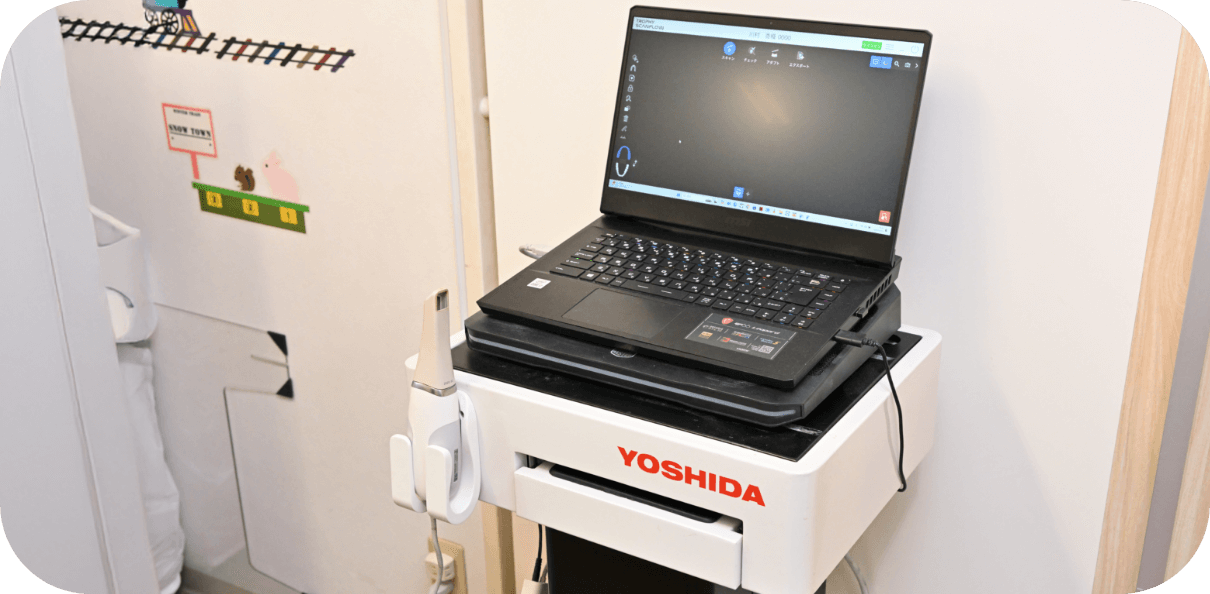 「YOSHIDA」と書かれた機器の上にノートパソコンが載っている医療現場の様子