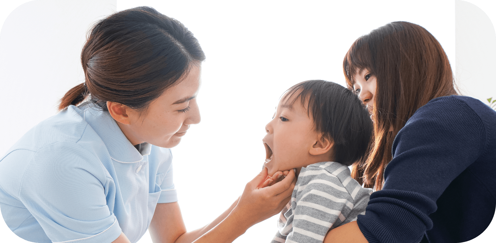 歯科衛生士が子どもの口を診察している様子で、母親がそばで見守っている